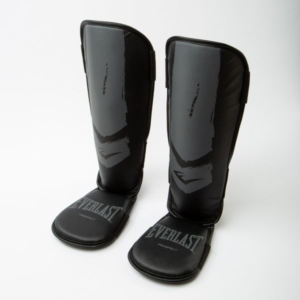 Parastinchi da ragazzi Everlast Prospect Youth di colore nero con dettagli grigi, logo Everlast bianco e struttura protettiva snodata in due pezzi per kickboxing e Muay Thai.