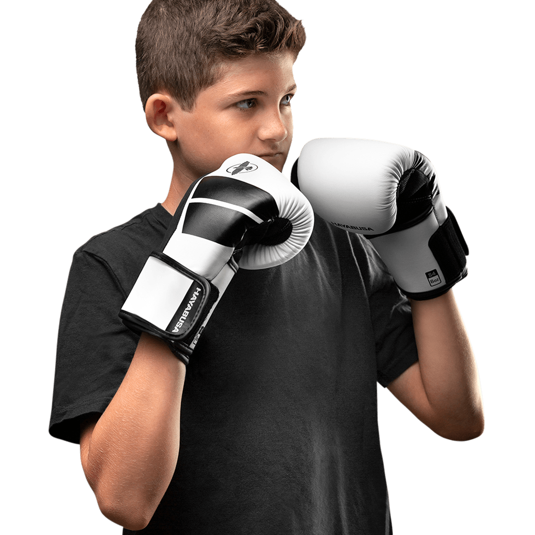 Piccola atleta che indossa i guantoni bianchi Hayabusa S4 durante una lezione di boxe