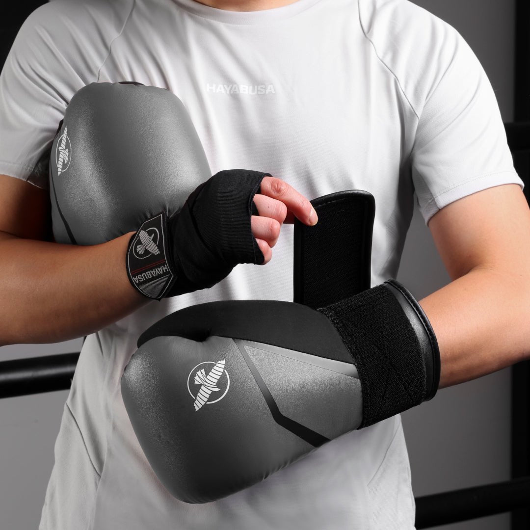 Graue Hayabusa E1-Boxhandschuhe, die beim Schlagen mit Fokushandschuhen getragen werden