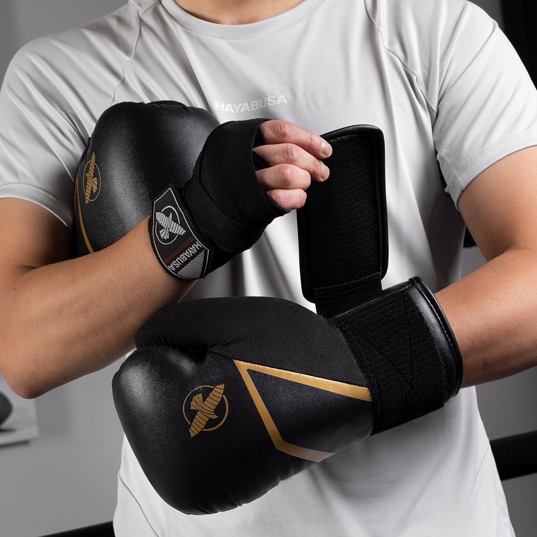 Hayabusa E1 schwarz-goldene Boxhandschuhe, die während eines Boxsacktrainings getragen werden