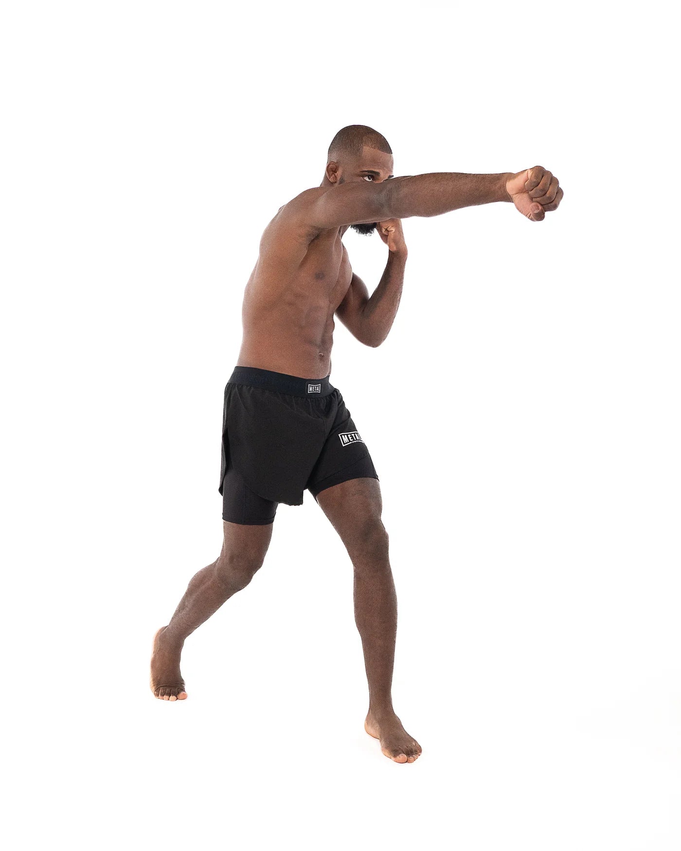 Atleta in azione che indossa i pantaloncini 2in1 Metal Boxe neri durante una tecnica di pugno