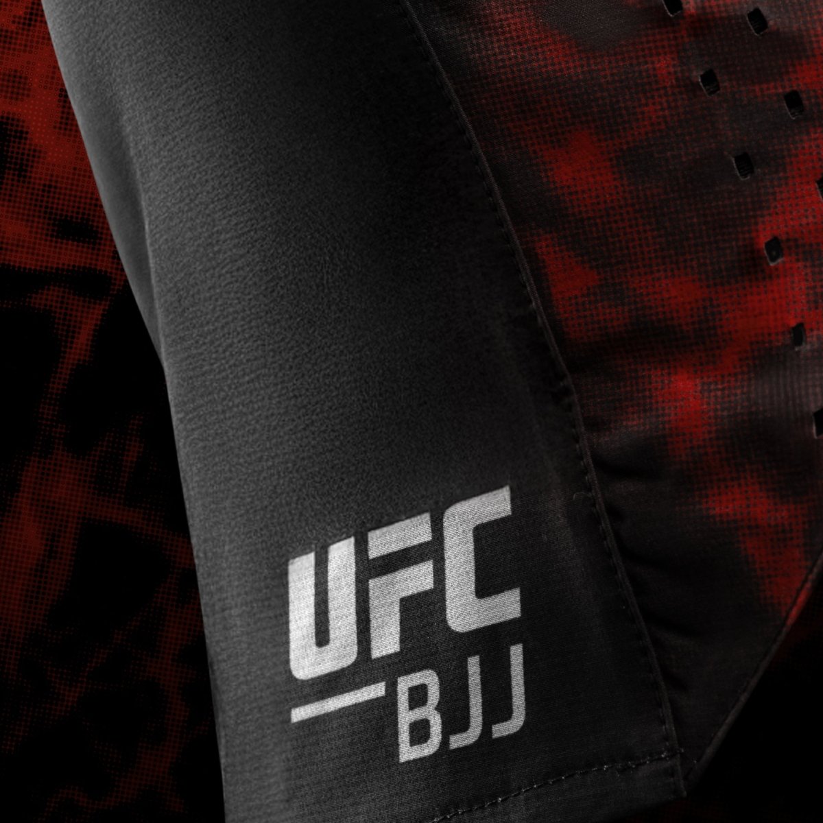 Primer plano del logotipo lateral de UFC BJJ en pantalones cortos de lucha para mujeres negros y rojos