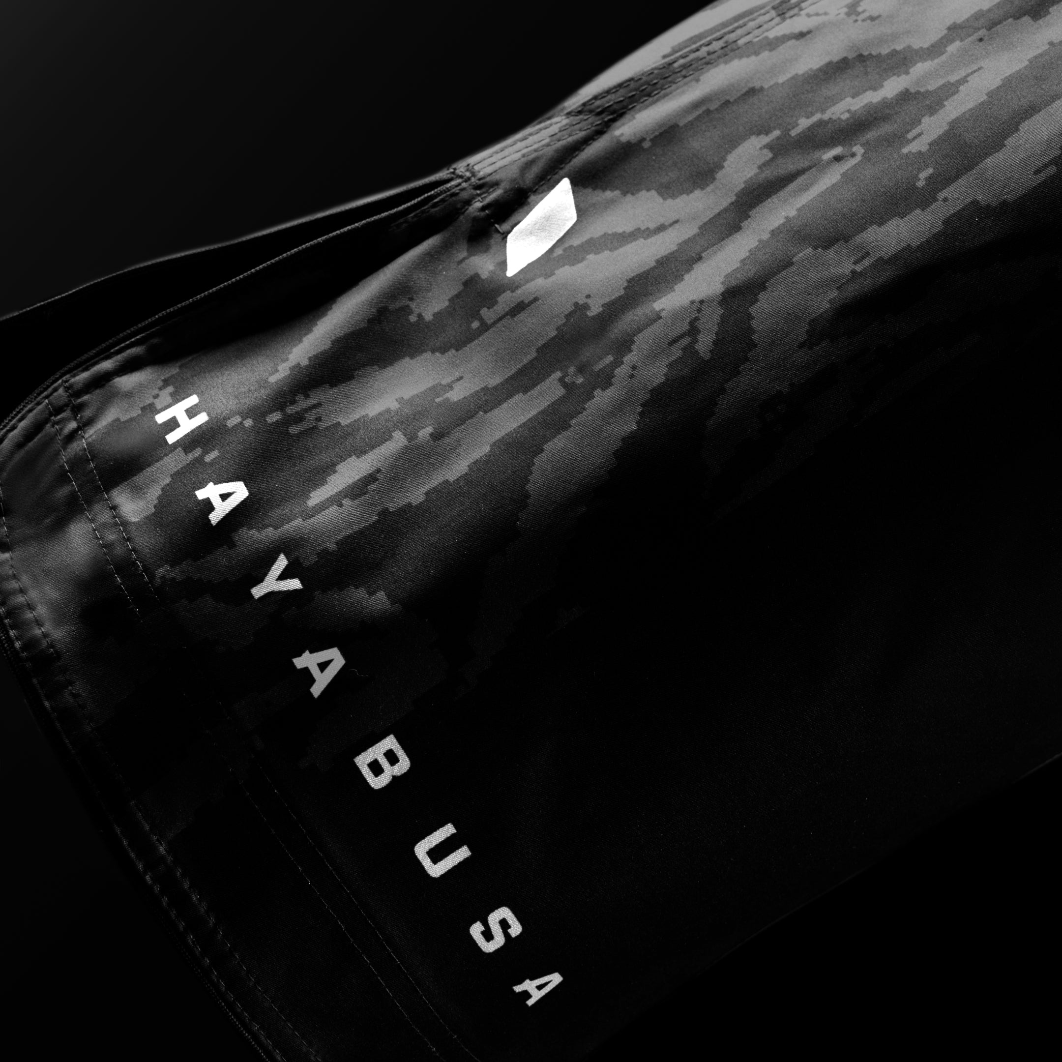 Dettaglio ravvicinato della scritta del brand Hayabusa sulla gamba dei pantaloncini neri Apex 3/4