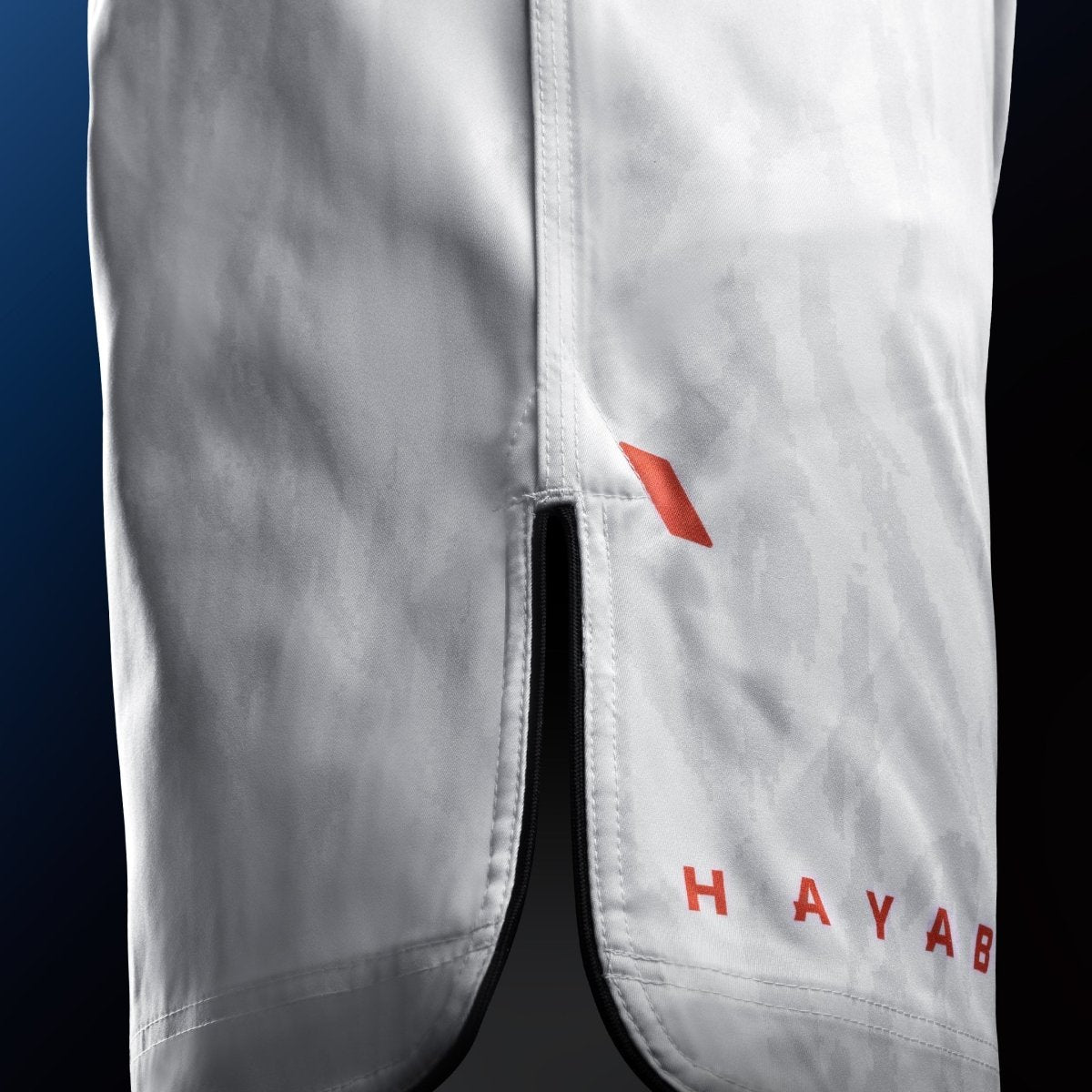 Vedere laterală a pantalonilor scurti MMA Hayabusa Apex Mid-Thigh albi cu detaliu de ventilație pentru mobilitate maximă