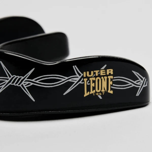 Dettaglio ravvicinato del logo gold LEONE x IUTER e della grafica Barbed Wire