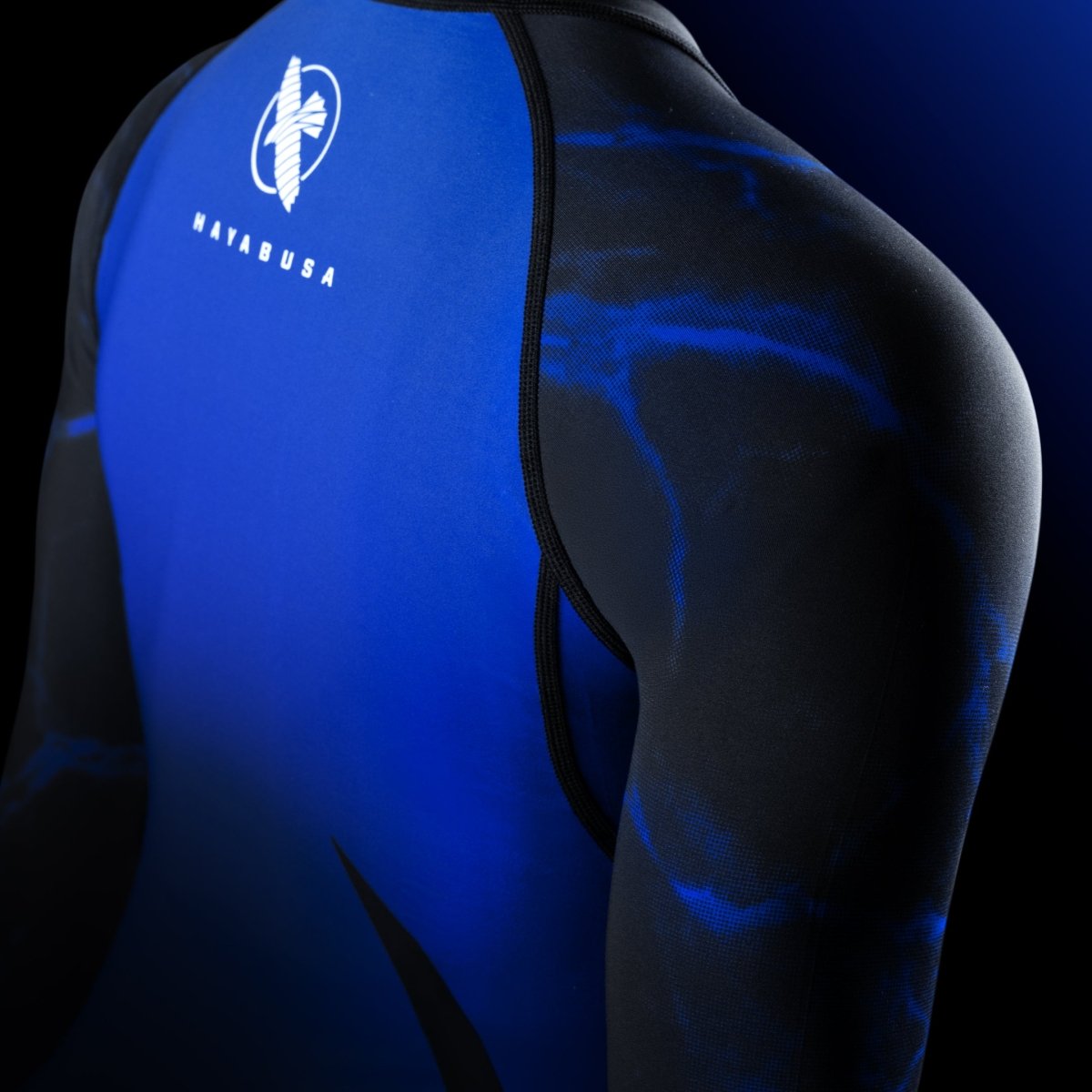 Detalle del hombro de la lycra UFC BJJ negra/azul, destacando el ajuste aerodinámico y el diseño oficial.
