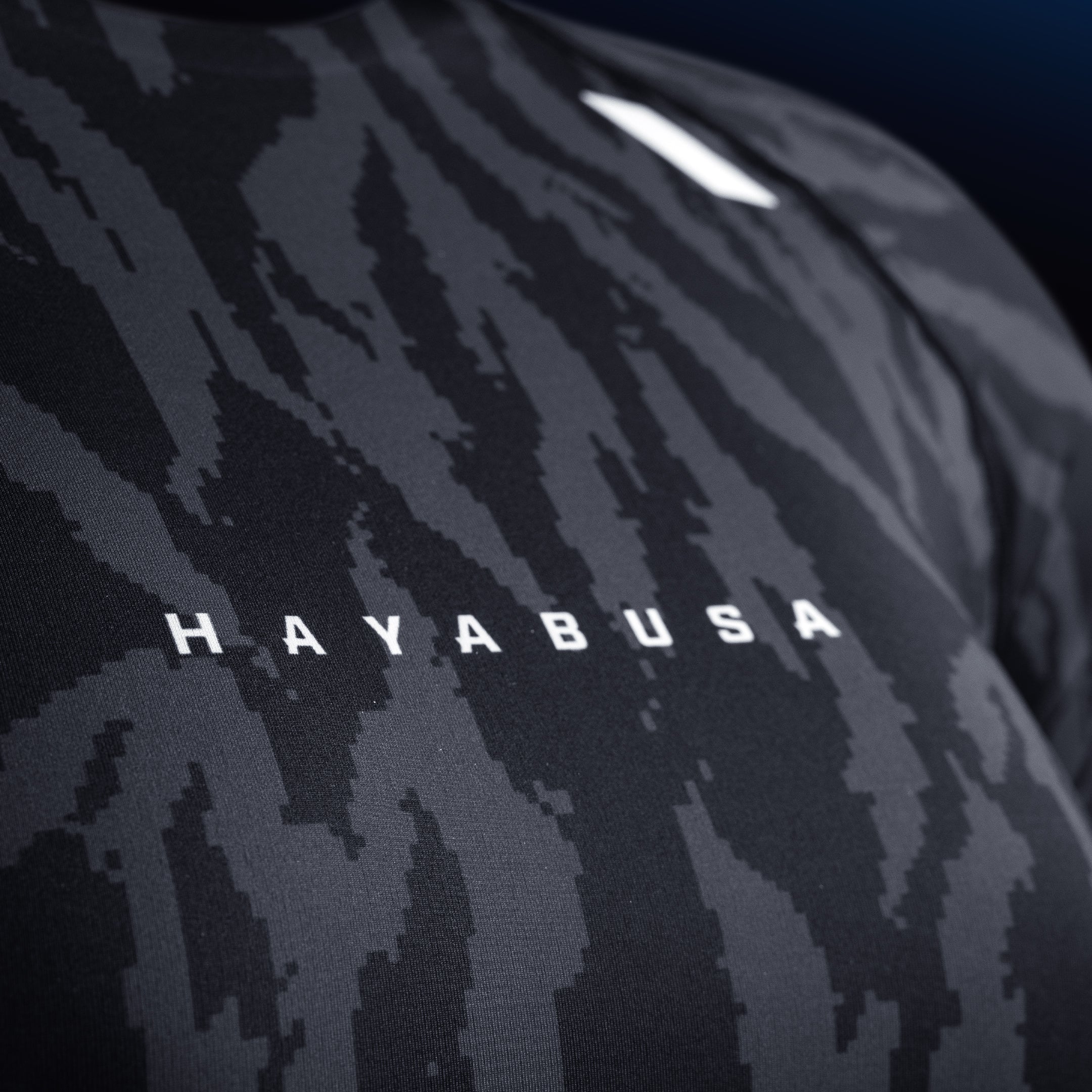 Dettaglio della scritta e del logo Hayabusa sul petto della rashguard nera, stampa resistente all'usura
