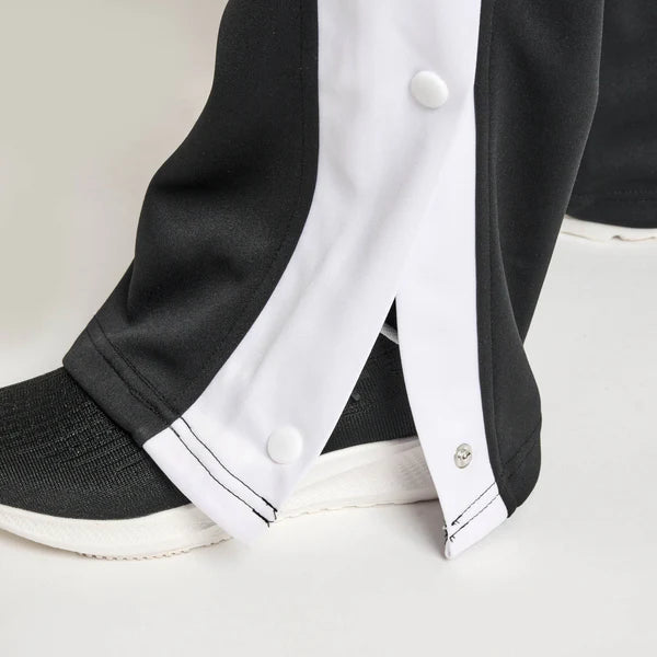 Primo piano dei bottoni laterali a strappo sui pantaloni neri della tuta Leone Stripe