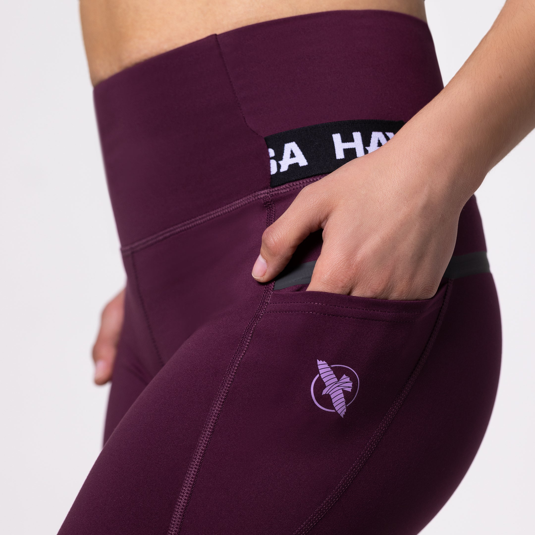 Dettaglio della tasca laterale a scomparsa sui leggings sportivi color vinaccia