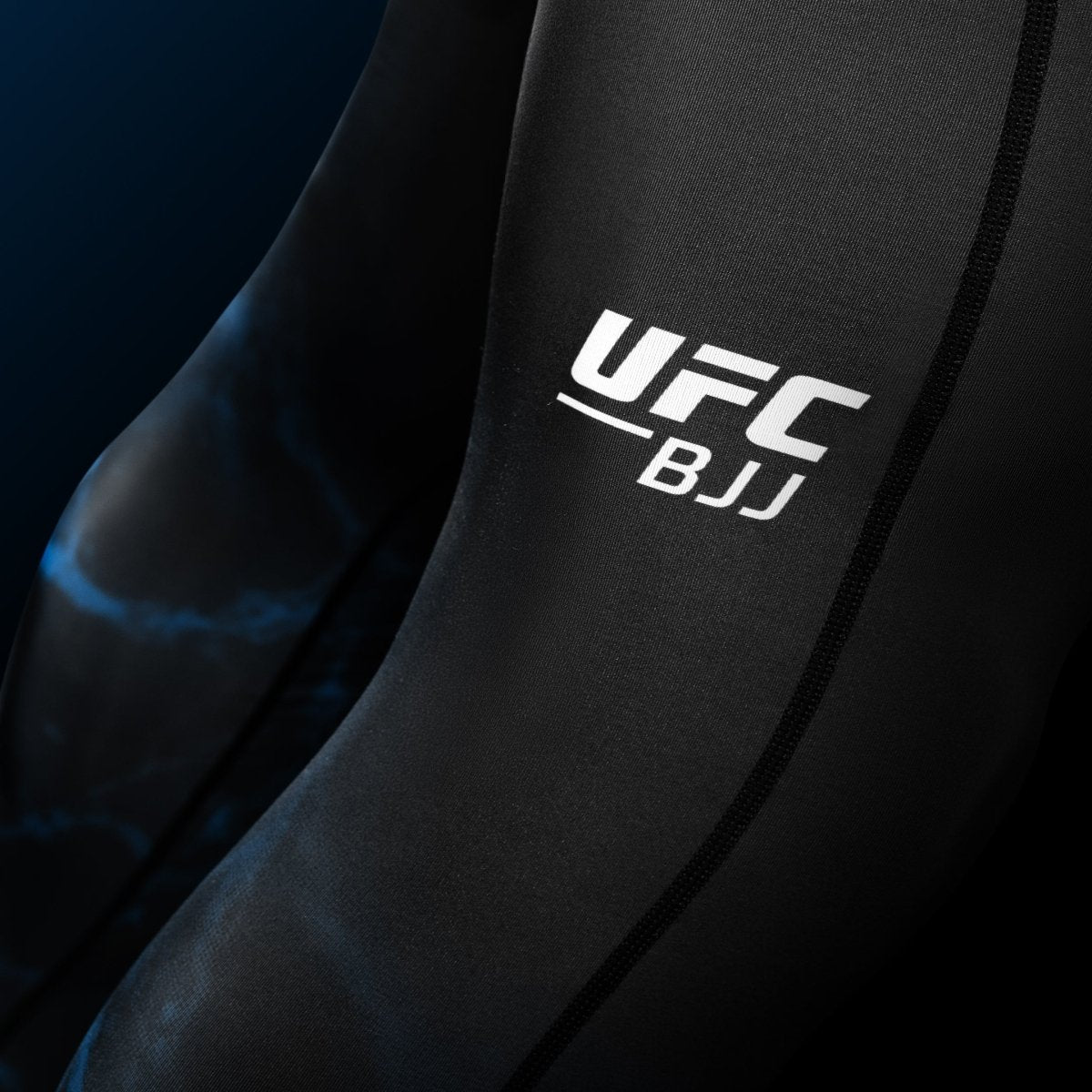 Närbildsdetalj av UFC-skriften tryckt på benet på de svarta och blå BJJ Spats-leggingsen