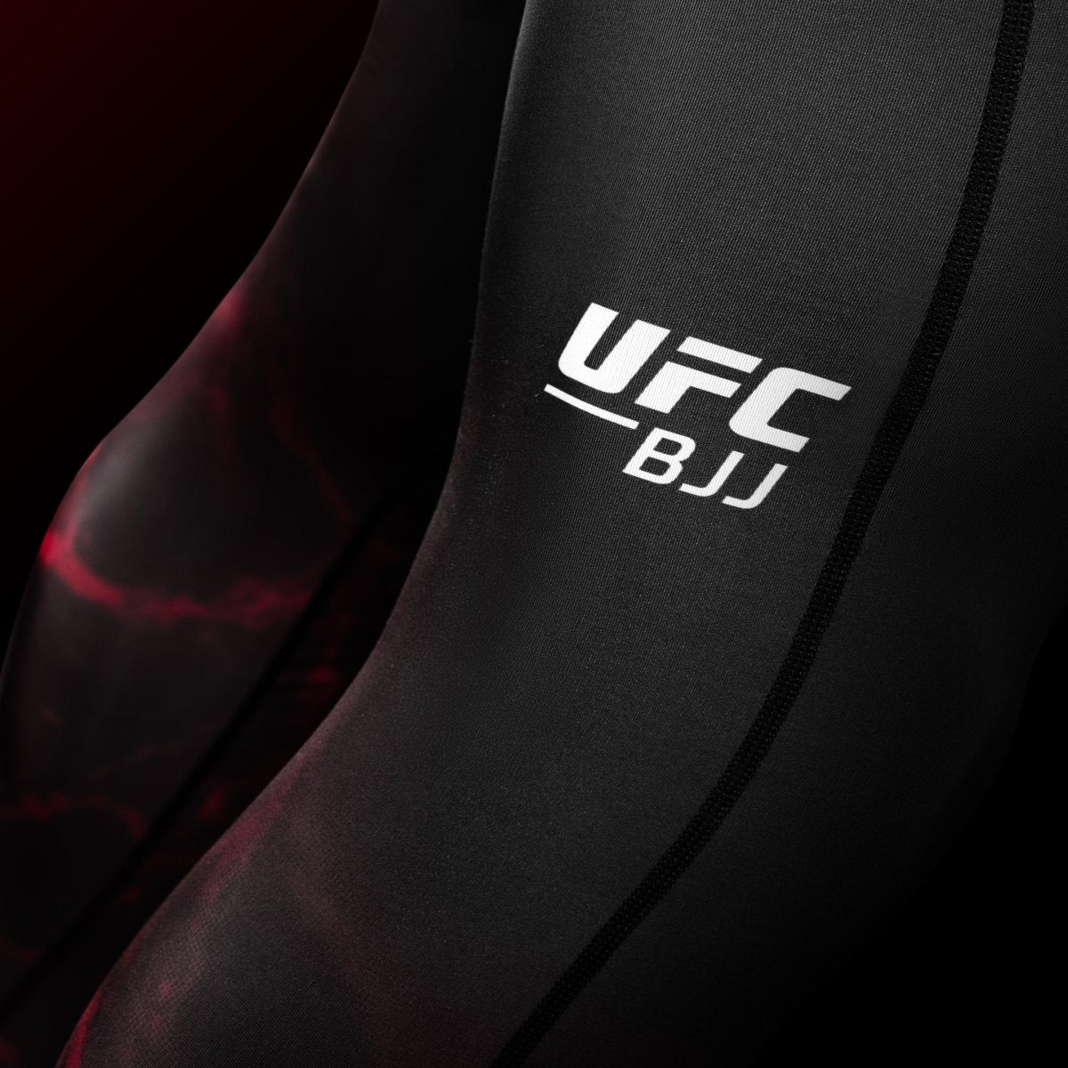 Närbild av UFC-grafiken på benet på de svarta och röda BJJ Spats-leggingsen, detalj av de förstärkta sömmarna