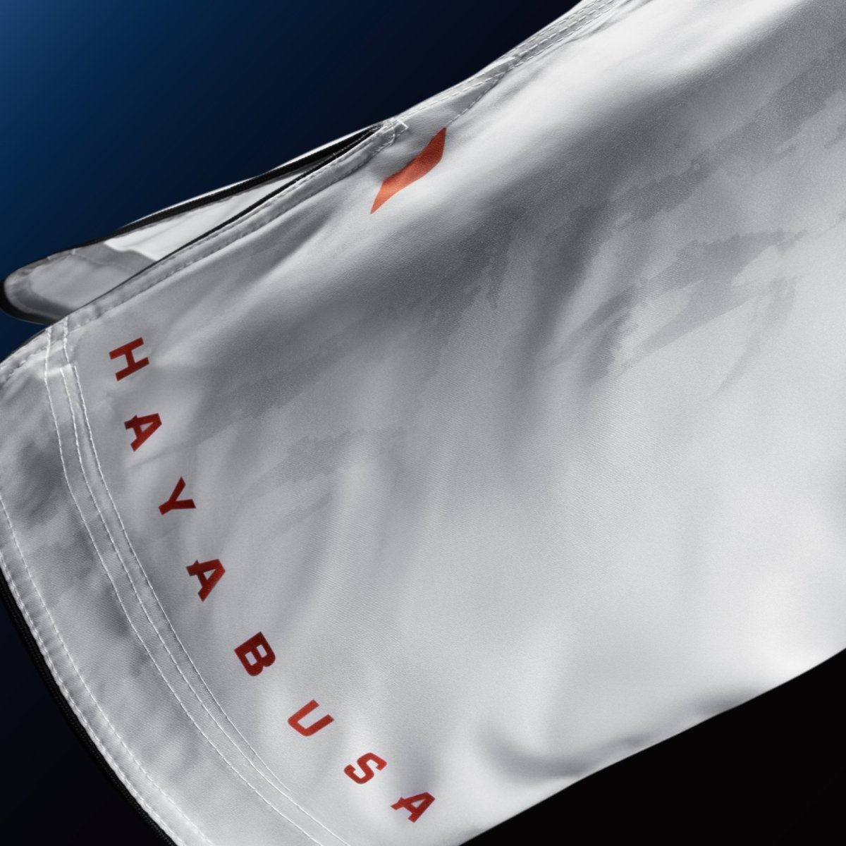 Detail van het Hayabusa-merkschrift op de pijp van de witte shorts voor BJJ en MMA