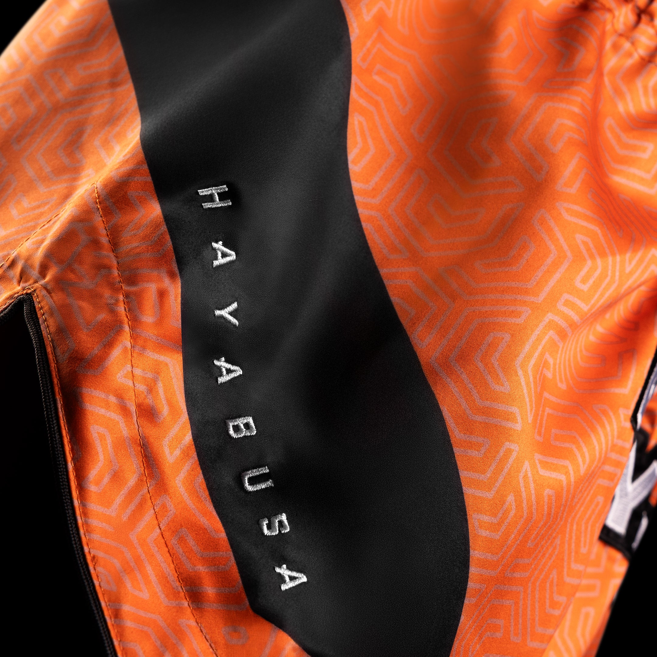 Dettaglio della finitura lucida e della resistenza del tessuto dei pantaloncini Hayabusa Core arancioni