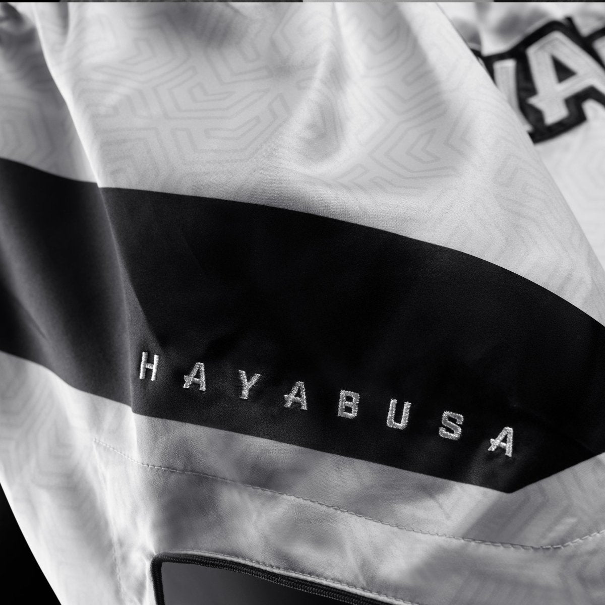 Detalj av det tekniska tyget och logotypen på de vita Hayabusa Core-shortsen