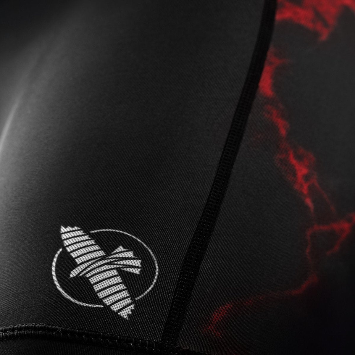Detalhe do logotipo oficial do UFC na perna do short feminino Vale Tudo preto e vermelho