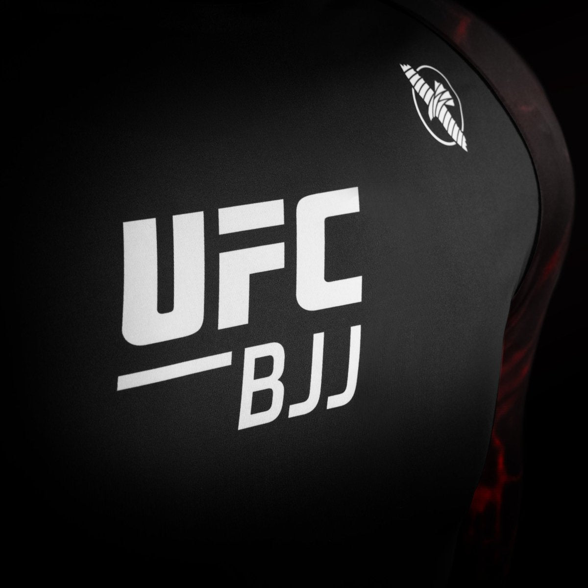 Détail du logo officiel de l'UFC sur le rashguard de compétition noir et rouge