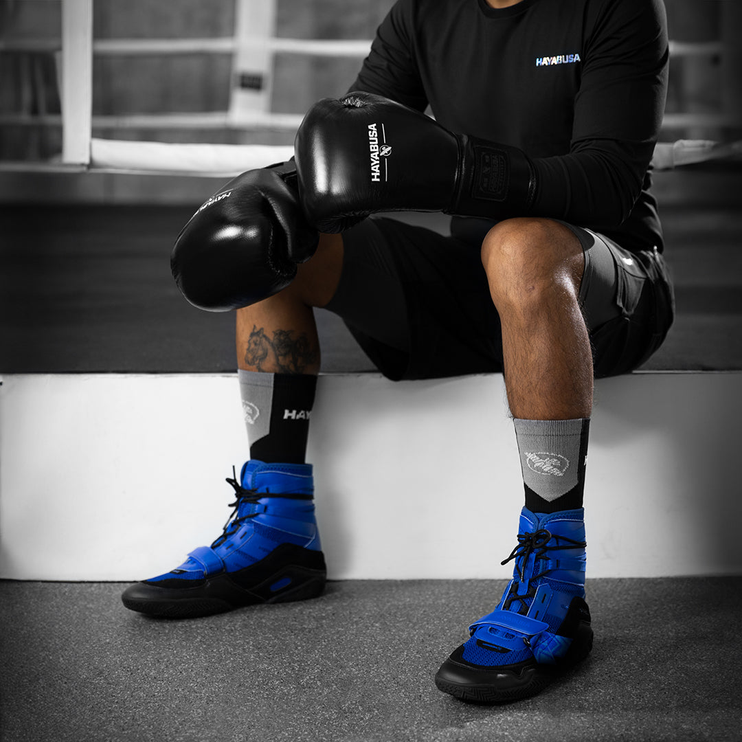 Dettaglio delle scarpe blu Hayabusa Strike indossate da un atleta