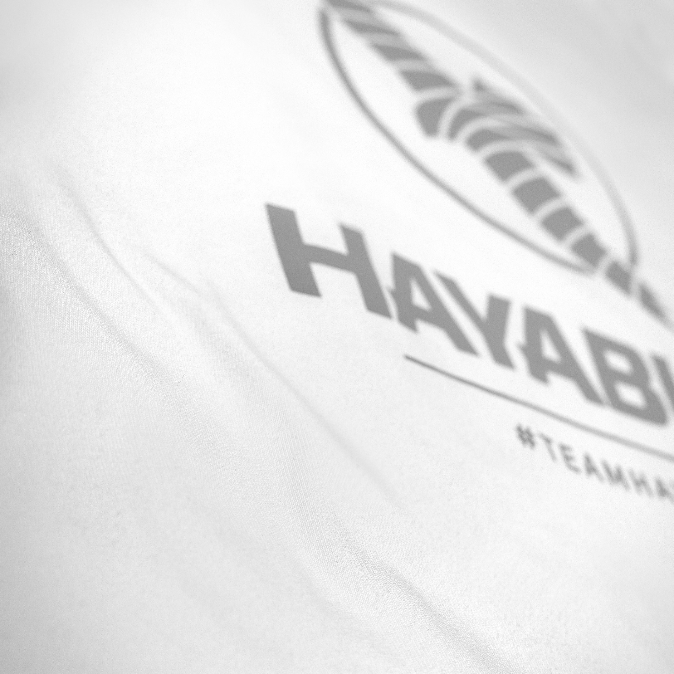 Dettaglio della stampa in silicone opaco #TeamHayabusa sulla t-shirt bianca